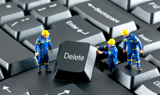 Team of construction workers working with DELETE button on a computer keyboard Team of construction workers working with DELETE button on a computer keyboard